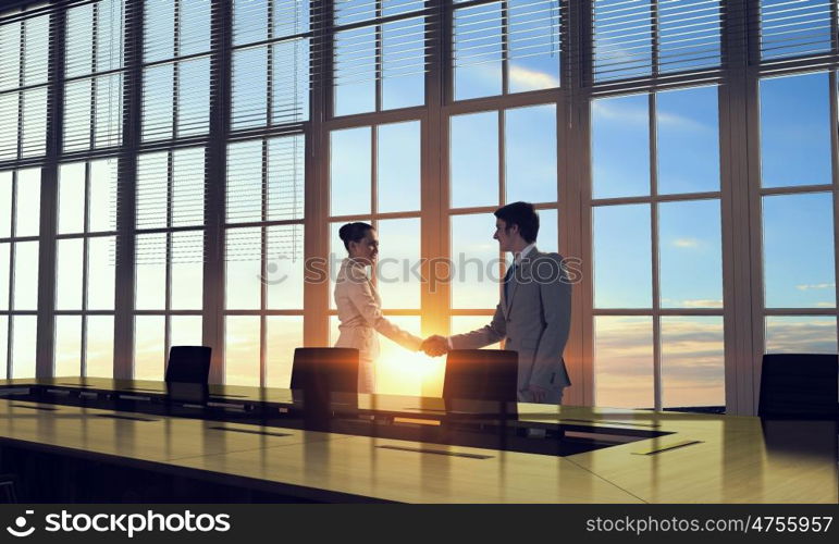 Silhouettes of Business People in Office. Mixed media. Two business people shaking hands in office in lights of sunset