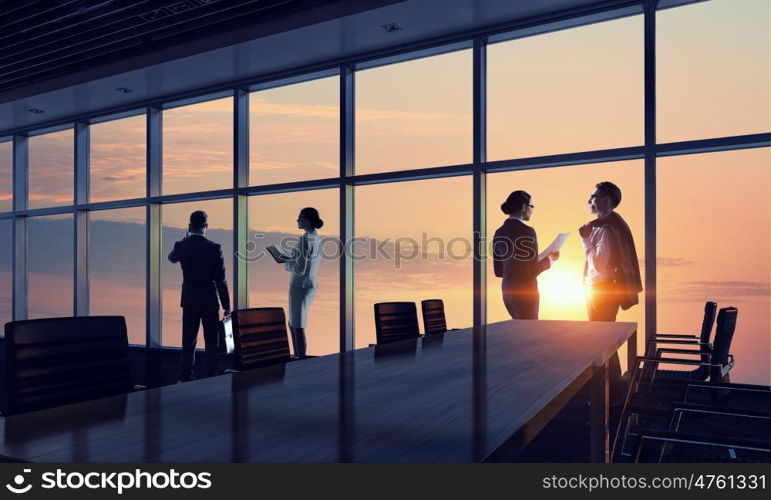 Silhouettes of Business People in Office. Mixed media. Group of business people working in office in lights of sunset