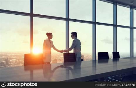 Silhouettes of Business People in Office. Mixed media. Two business people shaking hands in office in lights of sunset