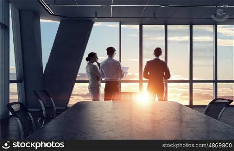 Silhouettes of Business People in Office. Mixed media. Group of business people working in office in lights of sunset