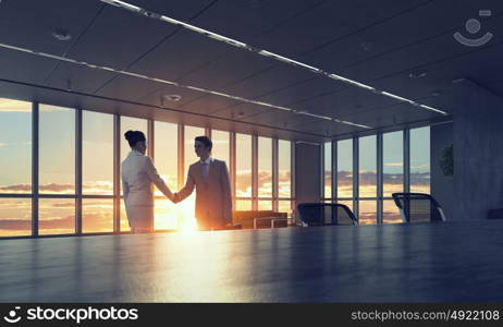 Silhouettes of Business People in Office. Mixed media. Two business people shaking hands in office in lights of sunset