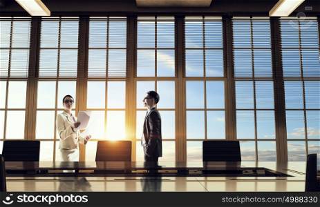 Silhouettes of Business People in Office. Mixed media. Two business people in office in lights of sunset