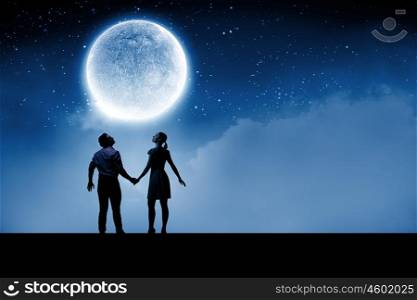 Silhouettes of couple against big moon at background