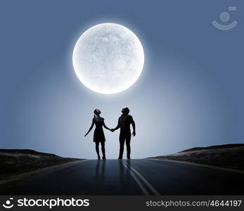 Silhouettes of couple against big moon at background