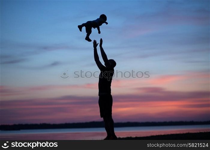 Silhouettes of dad tossing his child