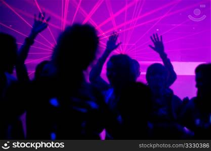 Silhouettes of dancing people having a celebration in a disco club, the light show is sending laser beams through the backlit scene, FOCUS IN ON THE BEAMS!