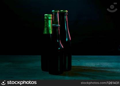 silhouettes of four beer bottles on a black background with blue lights that illuminate them on one side.. silhouettes of four beer bottles on a black background with blue lights that illuminate them on one side