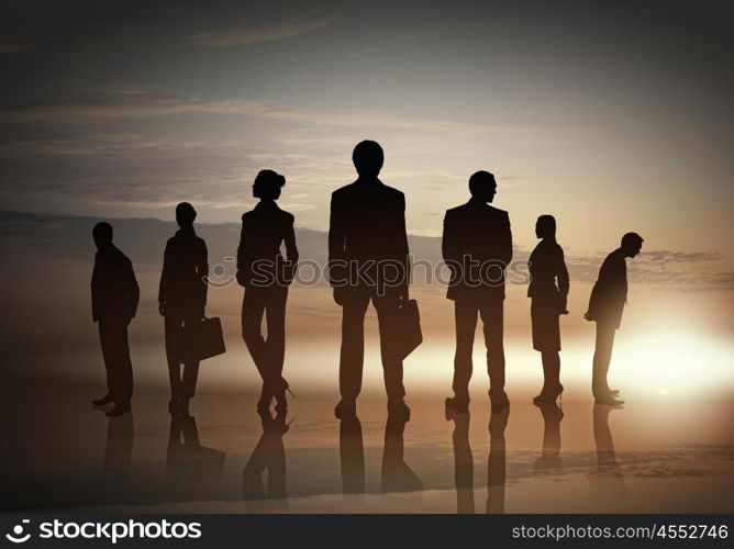 Silhouettes of group of business people standing in line on sunset background . They are proffesionals