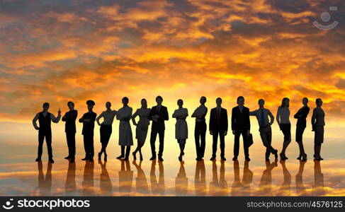 Silhouettes of group of business people standing in line on sunset background . They are proffesionals