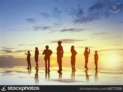 Silhouettes of group of business people standing in line on sunset background . They are proffesionals