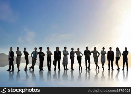 Silhouettes of group of business people standing in line on sunset background . They are proffesionals