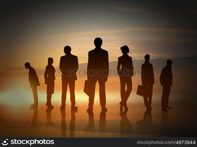 Silhouettes of group of business people standing in line on sunset background . They are proffesionals