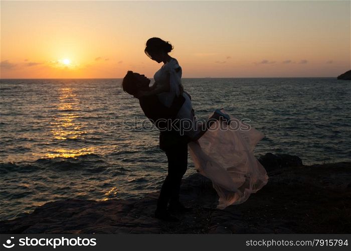 Silhouettes of man lifting girl. Romantic couple moments of the sunset.