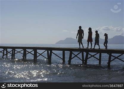 Silhouettes of parents and children (6-11) walking on jetty