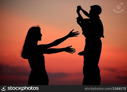 Silhouettes of parents with child against sea decline