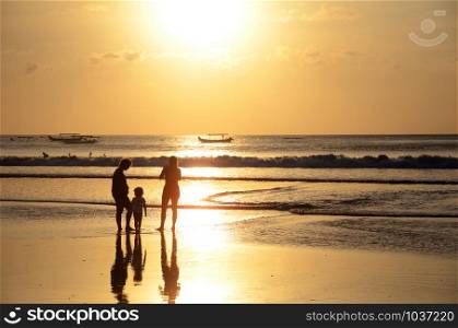 Silhouettes of people enjoying dramatic sunset at Kuta beach in Bali, Indonesia