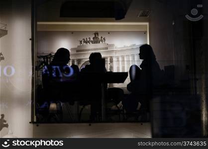 Silhouettes of people in the cafe. Through the window shot.