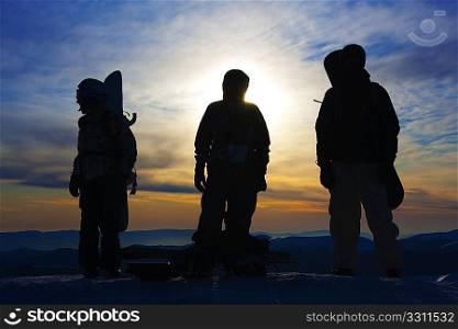 Silhouettes of the three backcountry freeriders in evening (Dragobrat ski resort, Ukraine).