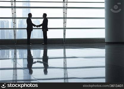 Silhouettes of two business men shaking hands