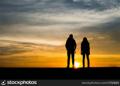 Silhouettes of two hikers with backpacks enjoying sunset. Travel. Silhouettes of two hikers with backpacks enjoying sunset. Travel concept.