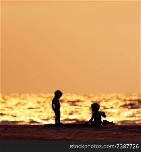 silhouettes of two young children beach sunset