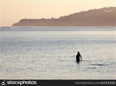 Silhoutted snorkling man on beach in Kauai at sunrise