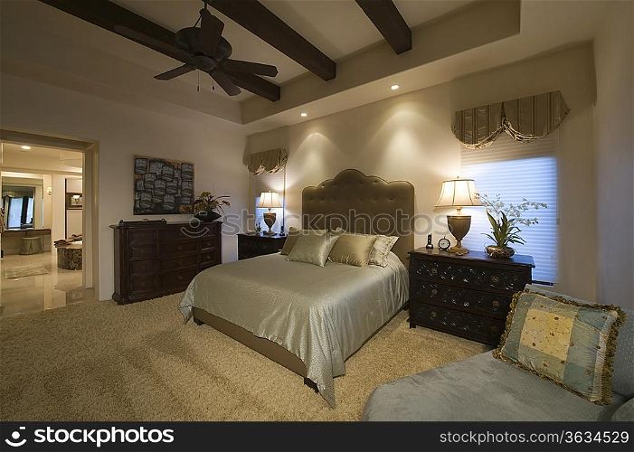 Silk bed cover on double bed in Palm Spring bedroom with beamed ceiling
