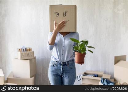 silly woman posing with box head plant hand while packing move