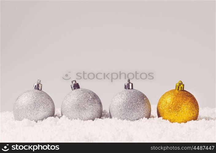 silver and golden decorative christmas balls on snow against grey background. decorative christmas balls