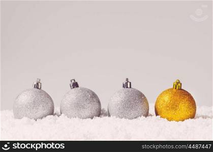 silver and golden decorative christmas balls on snow against grey background. decorative christmas balls