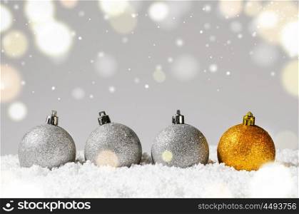 silver and golden decorative christmas balls on snow against grey festive background. decorative christmas balls