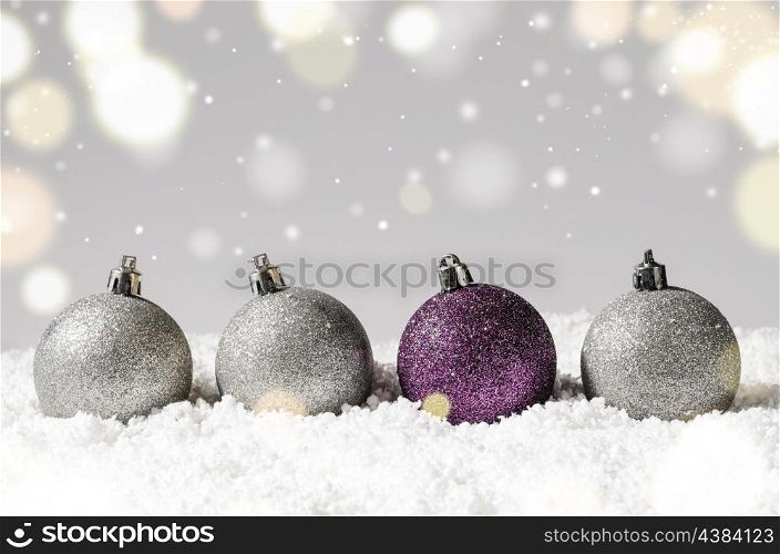silver and purple decorative christmas balls on snow against grey festive background. decorative christmas balls