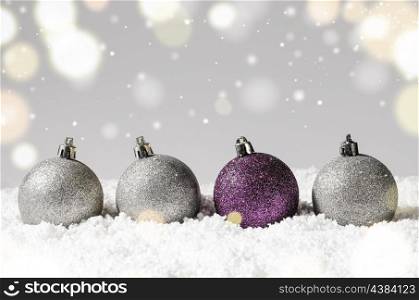 silver and purple decorative christmas balls on snow against grey festive background. decorative christmas balls
