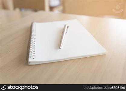 silver ballpoint pen and notebook notepad on wooden desk