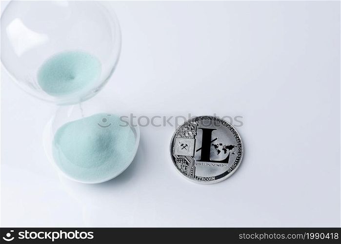 Silver bitcoin and hourglass on a white background. Digital currency.. Silver bitcoin and hourglass on a white background.