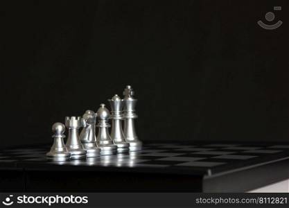 silver chess pieces on chess board isolate on black background