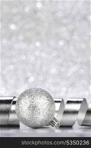 Silver Christmas decoration ball and ribbon on glitter background