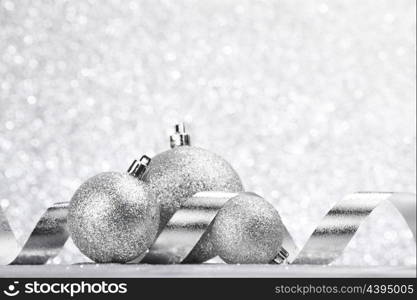 Silver Christmas decoration balls and ribbon on glitter background