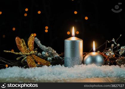 Silver christmas decoration on snow against dark background.