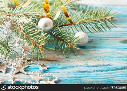 Silver Christmas decorations and fir branch on a blue wooden background