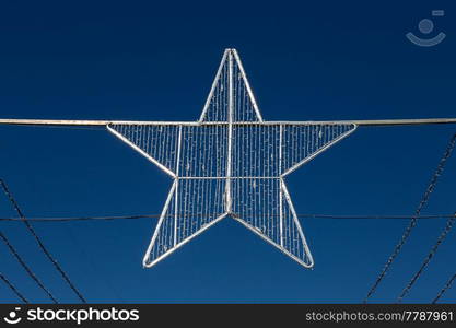 Silver christmas star in front of blue sky.. Silver christmas star in front of blue sky