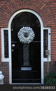 Silver christmas wreath with decorations on a door