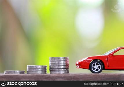 Silver coin of pile with red car model in concept savings to buy. Silver coin of pile with red car model in concept savings to buy a new car or value of car and journey insurance.