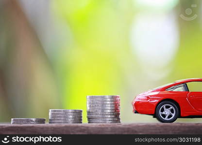 Silver coin of pile with red car model in concept savings to buy. Silver coin of pile with red car model in concept savings to buy a new car or value of car and journey insurance.