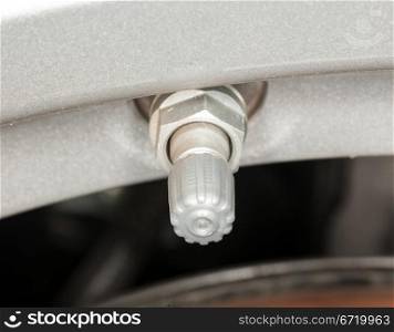 Silver colored tyre pressure valve on alloy wheel of car
