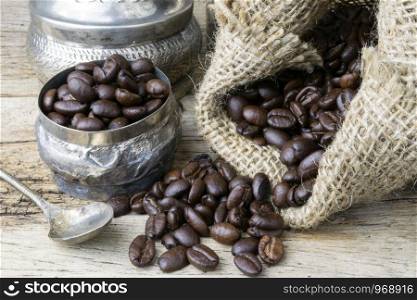 Silver cup and Coffee beans in sackcloth bag on wooden background