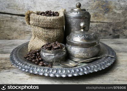Silver cup and Coffee beans in sackcloth bag on wooden background