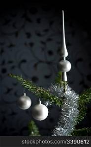 Silver decorated Christmas fir tree with balls and chains, black wallpaper in background