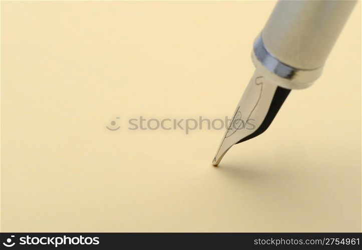 Silver fountain pen closeup. On a yellow paper