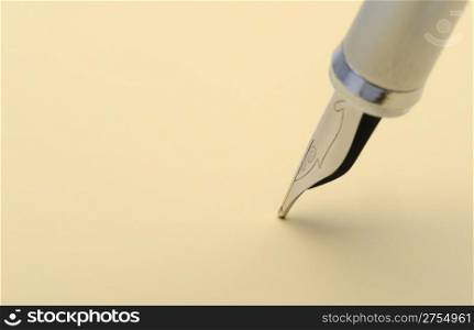 Silver fountain pen closeup. On a yellow paper